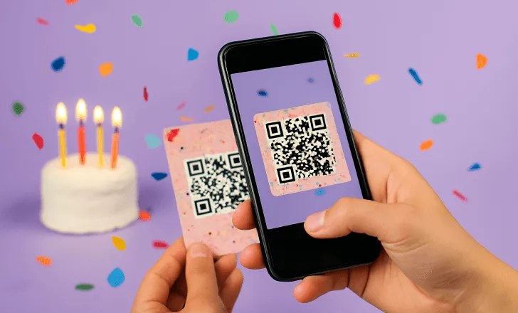 Primo piano di una persona che scansiona un QR code festivo su un biglietto decorato usando uno smartphone, con una torta di compleanno e coriandoli sullo sfondo.