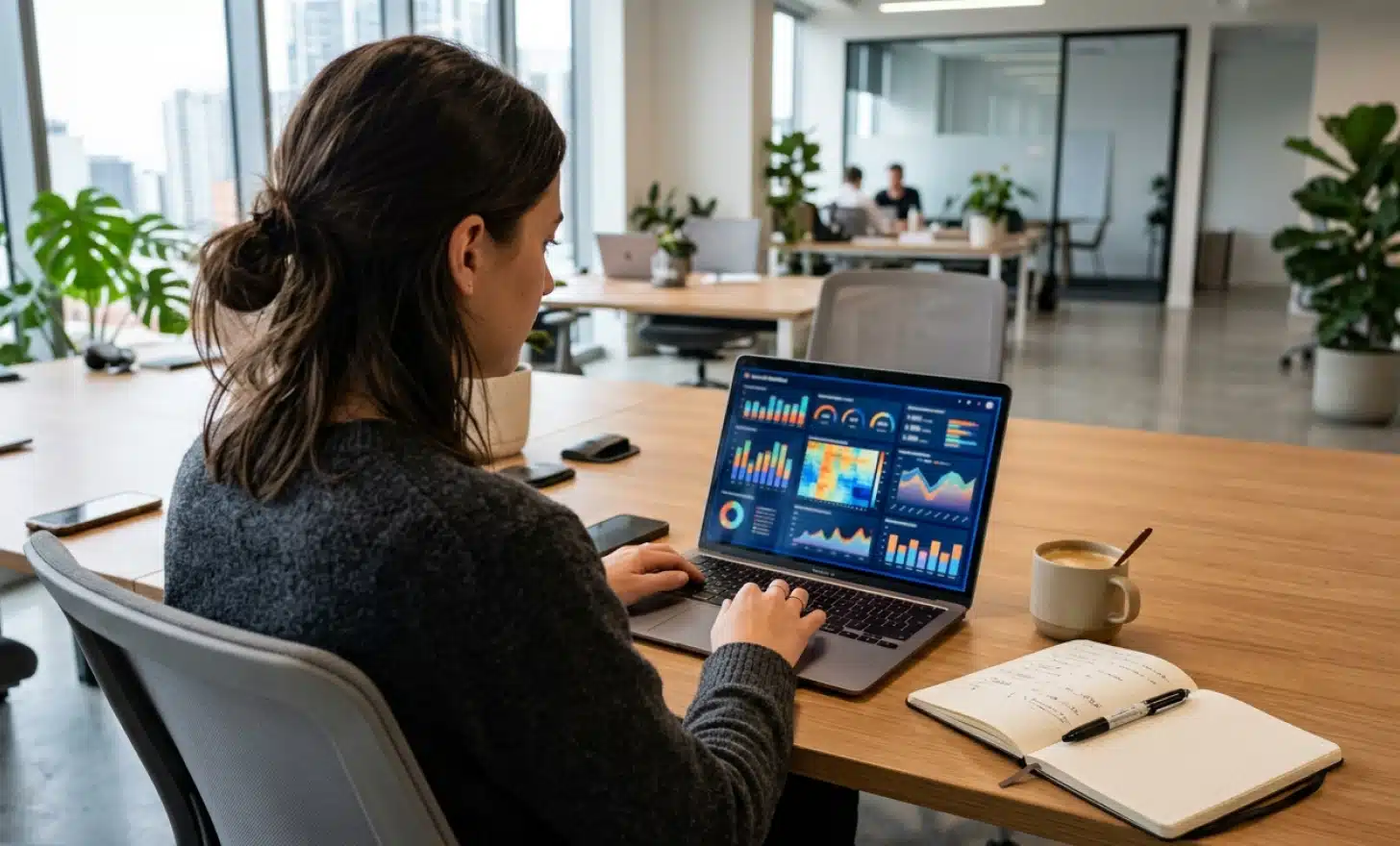 Analyst at a laptop reviewing dashboard charts in a modern workspace