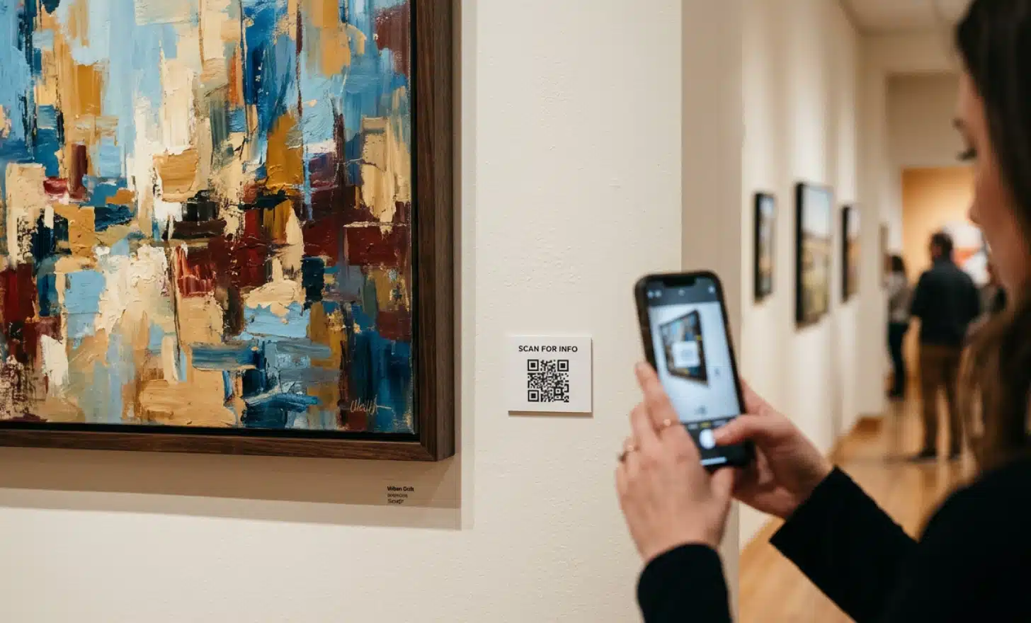 QR code dinâmico fixado ao lado de uma obra emoldurada, escaneado por um visitante para abrir sua página de catálogo digital.