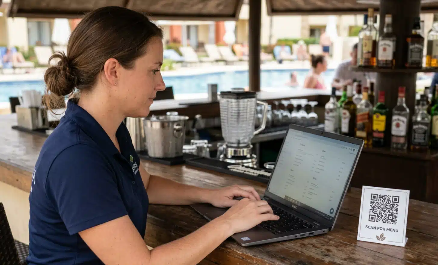 Pool bar manager updating a digital menu on a laptop beside a printed QR code card.