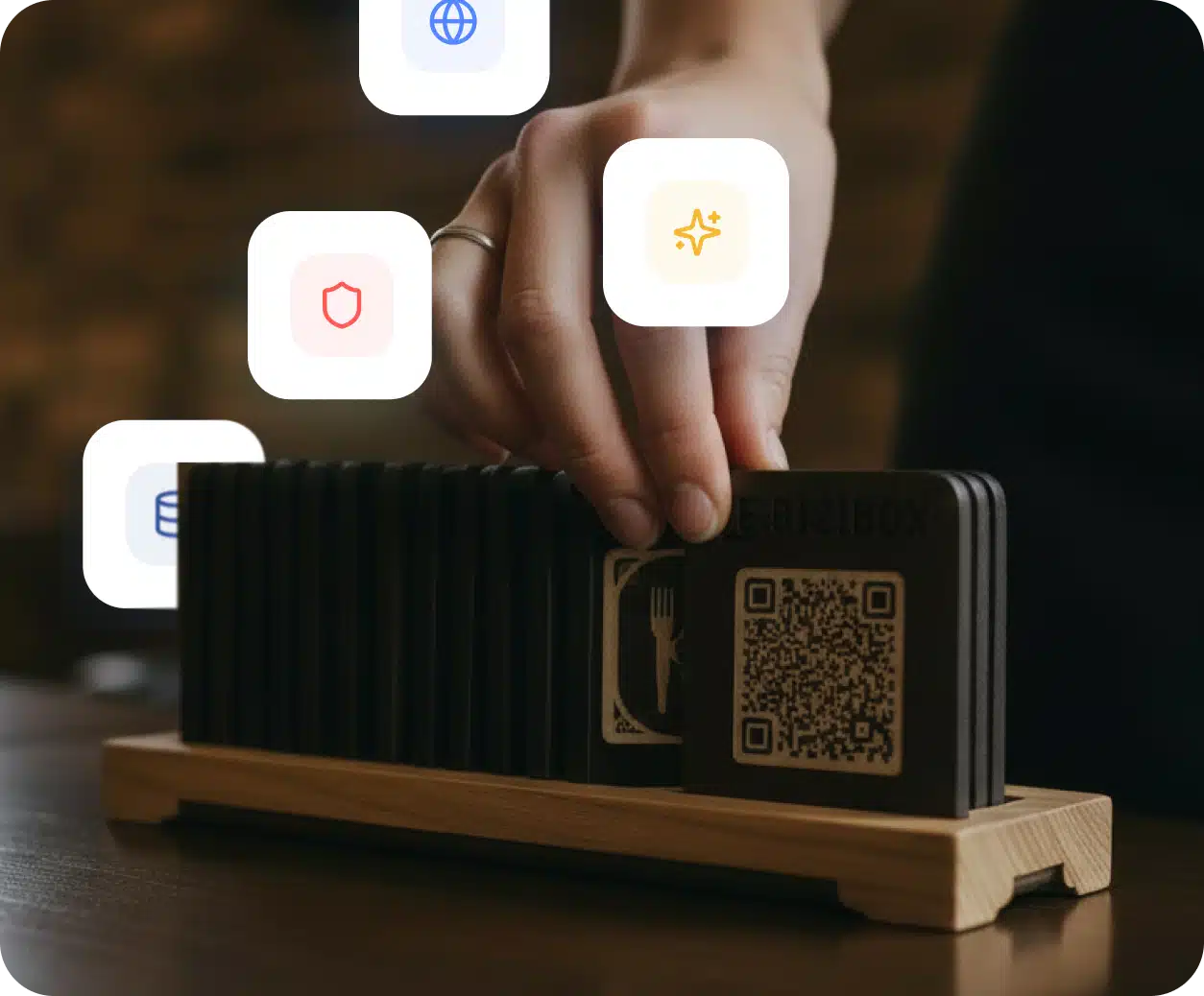 Una mano coloca un soporte QR de menú con IA sobre una mesa con iconos de funciones flotando