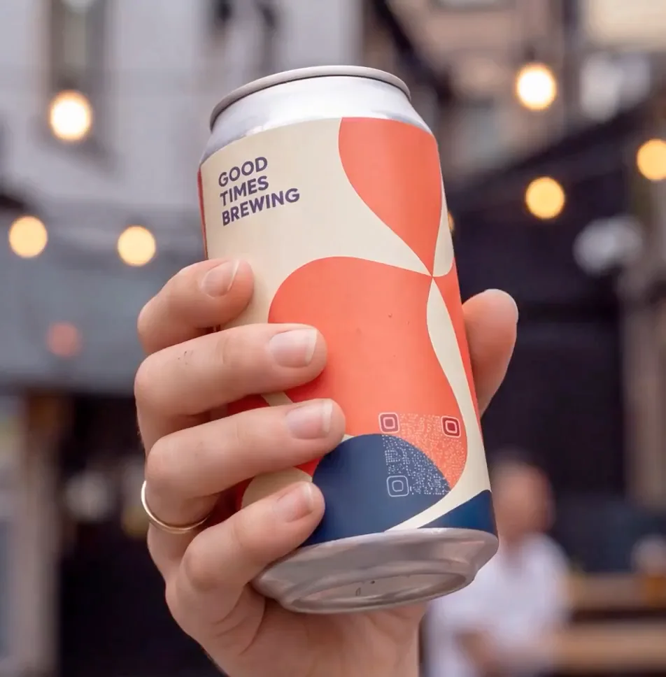 A hand holding a drinks can whose artwork hides a scannable QR code